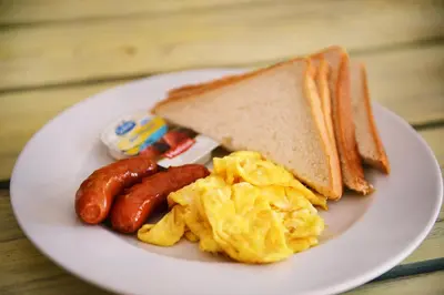a plate of breakfast food with eggs sausage and toast at Batey Hotel Boutique in Boca Chica