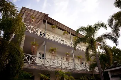 a white building with palm trees in front of it at Batey Hotel Boutique in Boca Chica