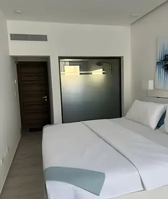 a bedroom with a large white bed and a door at Condominio de lujo Salida a playa Estilo Resort Muchas comodidades: 6 piscinas/TV/aire acondicionado in Punta Cana