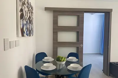 a dining room with a glass table and blue chairs at Condominio de lujo Salida a playa Estilo Resort Muchas comodidades: 6 piscinas/TV/aire acondicionado in Punta Cana