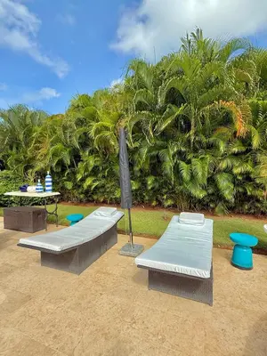 a patio with two beds and an umbrella at Hermosa y acogedora Villa en Casa de Campo in La Romana