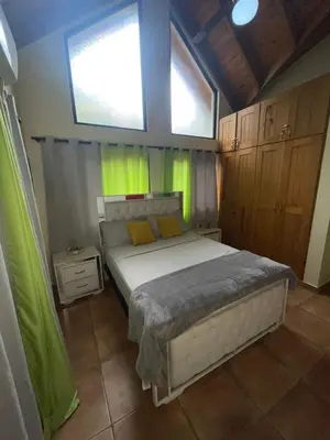 a bedroom with a bed with yellow and green curtains at cabaña de renta en Jarabacoa in Jarabacoa