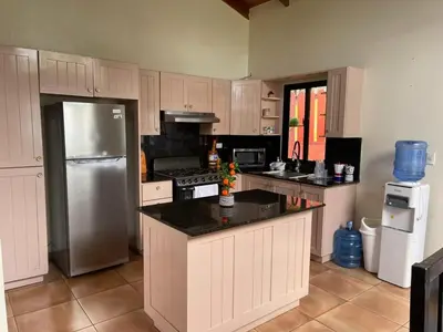 a kitchen with white cabinets and a stainless steel refrigerator at cabaña de renta en Jarabacoa in Jarabacoa
