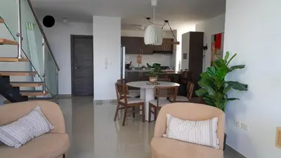 a living room with a table and chairs and a kitchen at Cozy Loft In The Heart of Santo Domingo Este in Juan López