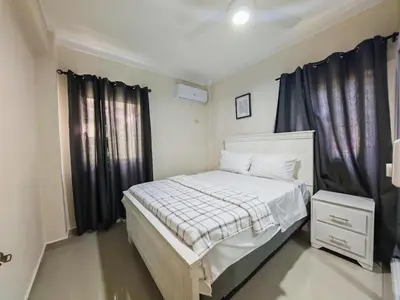 a bedroom with a white bed with black curtains at 2 Bdrm, Wi-fi, Hot Water Near Beach and River, 2R in Paraíso