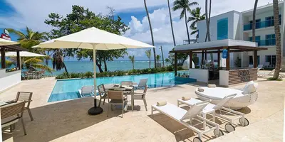 a pool with a table and chairs and an umbrella at Imperial Suite 1-bedroom ocean view and kitchen in Cabarete