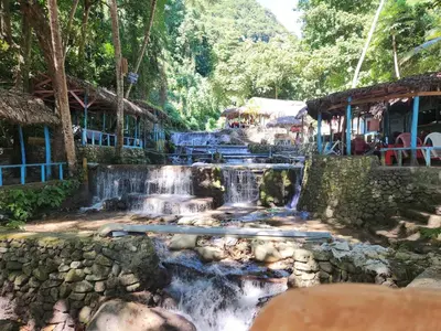 a waterfall in the middle of a forest with houses at 2 Bdrm 1 Bath Near River and Beach, 3L, Paraiso, Barahona in Paraíso