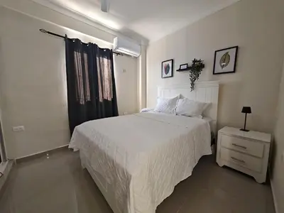 a bedroom with a white bed and a night stand at 2 Bdrm, 1 Bath, Wifi, Near River and Beach, 4L, Paraiso, Barahona in Paraíso
