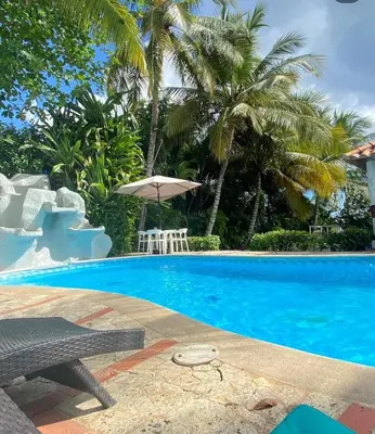 a swimming pool with a table and an umbrella at franchecis hostal cerca del mar in Juan Dolio