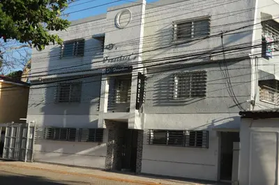 a white building with a clock on top of it at Horizonte Marino En De Franchecis Hostal in Juan Dolio