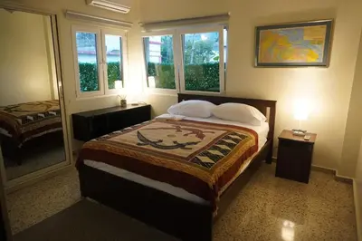 a bedroom with a bed and two windows at Beautiful Oceanfront Apartment Private Balcony in San Felipe de Puerto Plata