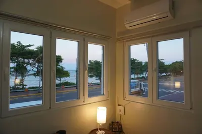 a room with three windows with a view of the ocean at Beautiful Oceanfront Apartment Private Balcony in San Felipe de Puerto Plata