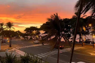 a view of a street with palm trees and a sunset at Beautiful Oceanfront Apartment Private Balcony in San Felipe de Puerto Plata