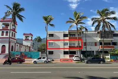 a building with palm trees in front of a street at Beautiful Oceanfront Apartment Private Balcony in San Felipe de Puerto Plata