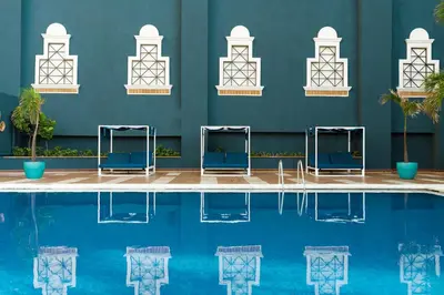 a swimming pool with blue chairs in front of a blue wall at Catalonia Santo Domingo in Santo Domingo