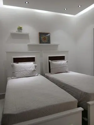 two beds in a room with white walls at a wonderful apt, close to everything you need in Santo Domingo