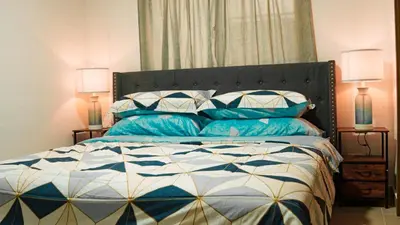 a bed with blue and white pillows and two lamps at Relaxing & New Retreat 3 bedroom riviera Verde in Santo Domingo