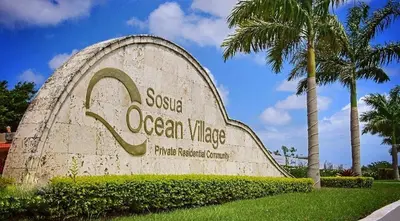 a sign for a ocean wave sign with a palm tree at Villa Jasmine Ocean Village in Sosúa