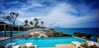 a swimming pool with a view of the ocean at Villa Jasmine Ocean Village in Sosúa