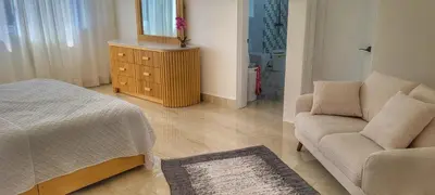 a bedroom with a bed and a chair and a mirror at Villa Jasmine Ocean Village in Sosúa