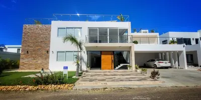 a white house with a car parked in front of it at Apt Jasmine Ocean Village in Sosúa