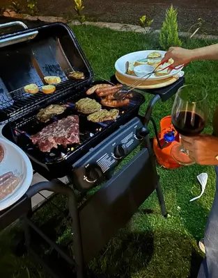 a person cooking food on a grill with a plate of food at La Gloria in San José de Ocoa