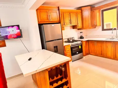 a kitchen with wooden cabinets and a stainless steel refrigerator at Enjoy Huge 4 bedrooms, and 3 bathrooms, 8 new apartments in Santiago de los Caballeros