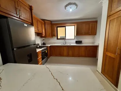 a kitchen with wooden cabinets and a stainless steel refrigerator at Enjoy Huge 4 bedrooms, and 3 bathrooms, 8 new apartments in Santiago de los Caballeros