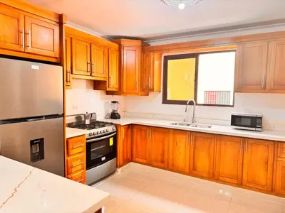 a kitchen with wooden cabinets and a stainless steel refrigerator at Enjoy Huge 4 bedrooms, and 3 bathrooms, 8 new apartments in Santiago de los Caballeros