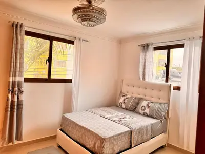 a small bedroom with a bed and two windows at Enjoy Huge 4 bedrooms and 3 bathrooms in Santiago de los Caballeros