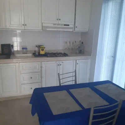a kitchen with white cabinets and a blue table and chairs at Tribe Inn & Rooftop lounge in Bayahibe