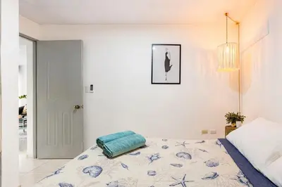 a white bedroom with a bed and a chandelier at Casa de las Mariposas - near the beach in Río San Juan