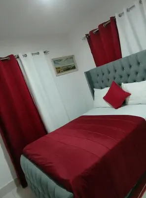 a bedroom with a bed with red and white pillows at Apartamento Alto del valle de 2 habitaciones in Santiago de los Caballeros