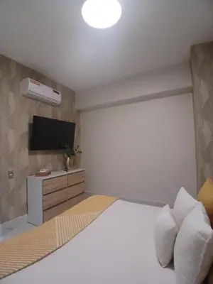 a bedroom with a bed with a tv on the wall at Downtown, Cozy and Modern! in Santo Domingo