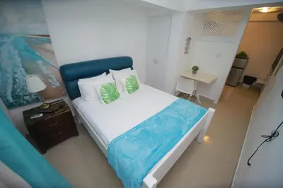 a bedroom with a large bed with a blue headboard at El Mar Azul Franchecis hostal in Juan Dolio