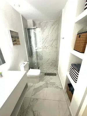 a white bathroom with a toilet and a shower at New Jacuzzi Beach Fun 2 bedroom at Cana Rock Star in Punta Cana