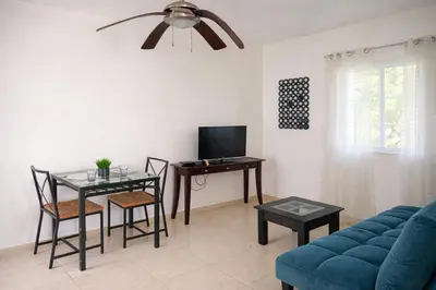 a living room with a blue couch and a table with a tv at Villa La Olita in La Puntica de Juan Dolio
