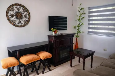 a living room with a television and a table and stools at Villa La Olita in La Puntica de Juan Dolio