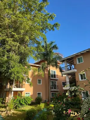 an apartment building with a palm tree and flowers at Cozy 3 Bedroom Apartment with Pool & Private Beach in Bávaro Punta Cana in Punta Cana