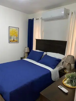 a bedroom with a blue bed and a table at Isidro 102 Comfrot Stay in San Isidro