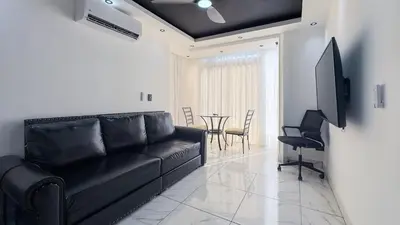 a living room with a black couch and a table at One Bedroom Apartment - Wi-Fi - BBQ in Sosúa