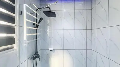 a shower in a bathroom with white tiles at One Bedroom Apartment - Wi-Fi - BBQ in Sosúa