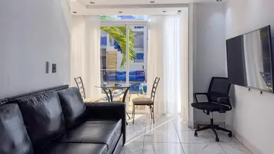 a living room with a black couch and a table at One Bedroom Apartment - Wi-Fi - BBQ in Sosúa