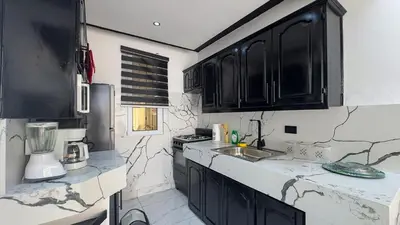 a kitchen with black cabinets and marble counter tops at One Bedroom Apartment - Wi-Fi - BBQ in Sosúa