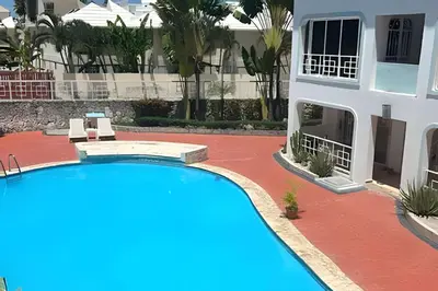 a swimming pool in front of a house at Los Corales Moderno Apto: Piscina y Playa 10 min in Punta Cana