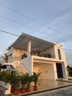 a white house with palm trees in front of it at Luxurious 3-Bedroom Apartment in Juan Dolio with Pool Access in Juan Dolio