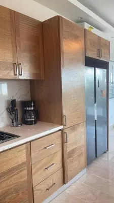 a kitchen with wooden cabinets and a refrigerator at Spacious 3-Bedroom Apartment with Pool Access in Juan Dolio in Juan Dolio