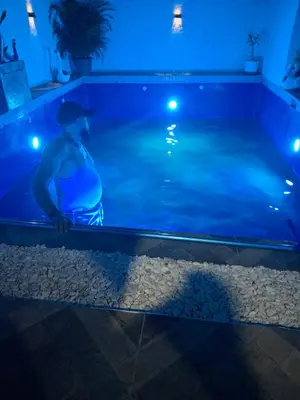 a man standing next to a swimming pool at night at Villa Manuel Rodriguez