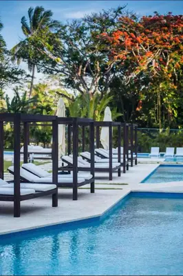 a row of lounge chairs next to a swimming pool at Presidential Suites 1 bedroom with kitchen in Cabarete
