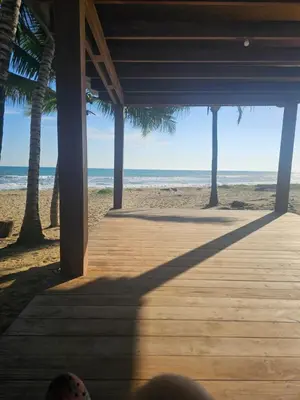 a person sitting on a wooden porch looking at the beach at Cristamar in Cabarete